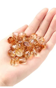Detail view of high-quality transparent yellow citrine faceted crystal beads held in a hand.