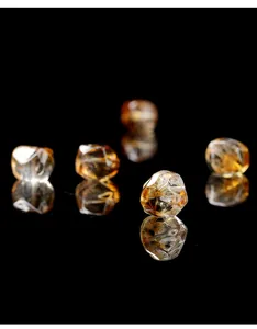 Close-up view of faceted natural citrine beads with high transparency on black reflective surface