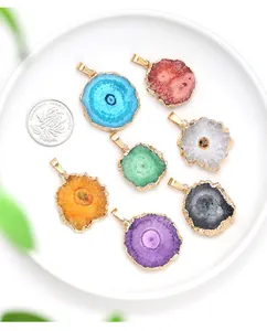 Detail of multi-colored agate druzy slice pendants with gold-plated edges on white tray