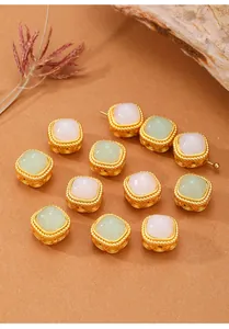 Detailansicht quadratischer goldener Filigran-Zwischenperlen mit rosa und grünen Jadeimitaten.