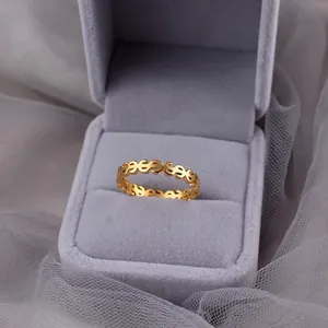 Close-up of a gold-plated ring featuring a repetitive dollar sign pattern in a gift box