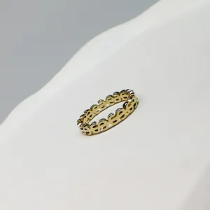 Close-up of a minimalist gold-toned ring featuring a recurring dollar sign pattern