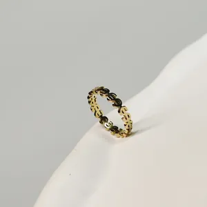 Detailed macro shot of gold dollar sign pattern ring on a white minimalist background.