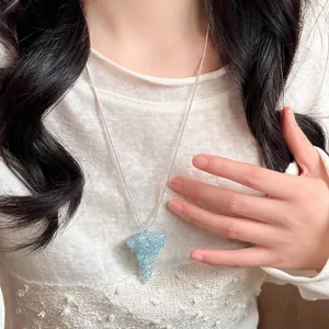 Lange verstellbare Halskette mit hellblauem Kristalltraubenanhänger an einem Modell