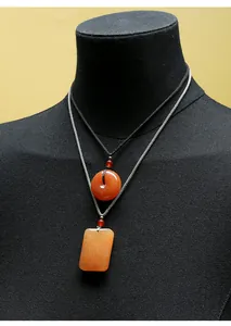 Vue détaillée de deux pendentifs en jade jaune dragon sur un mannequin noir élégant.