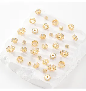 Detailed macro shot of various gold-plated zircon spacer beads on a textured white stone