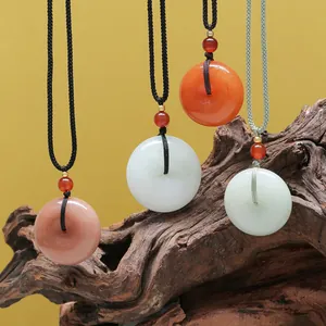 Pendentifs Ping'an en jade naturel multicolores suspendus sur un support en bois rustique.