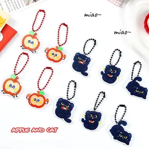 Close-up of various cute apple and black cat acrylic keychains with bead chains.