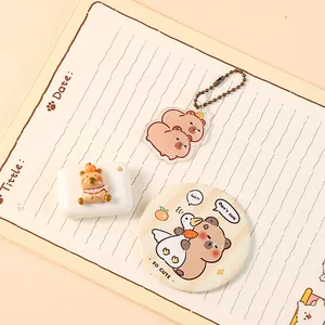 Primer plano de un lindo set de papelería Capybara con llavero, espejo y caja de regalo.