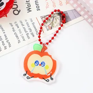 Close-up detail of a cute apple-shaped acrylic keychain with a vibrant red ball chain