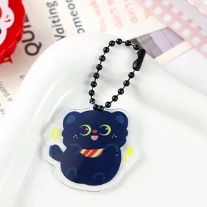 Close-up of cute dark blue cat acrylic keychain with moon eyes and black ball chain