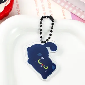Detail view of a cute dark blue acrylic cat keychain featuring a black ball chain