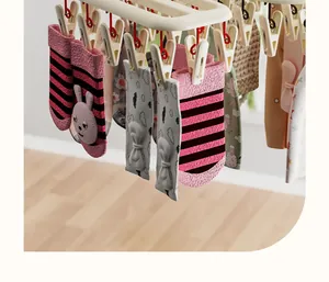 Detailed view of a multi-clip laundry hanger drying cute pink rabbit and bow baby socks
