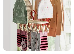 Detail of multi-clip laundry rack drying baby socks and hats in a sunlit balcony