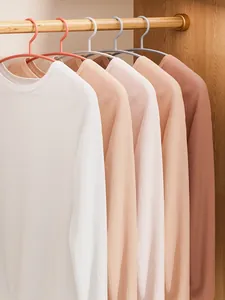 Detail view of multi-colored non-slip hangers holding shirts in a wooden wardrobe