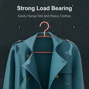 Pink non-slip clothes hanger holding heavy wet coat on a dark background
