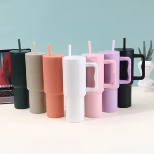 Seven colorful 40oz insulated tumblers with handles and straws in a modern office setup.