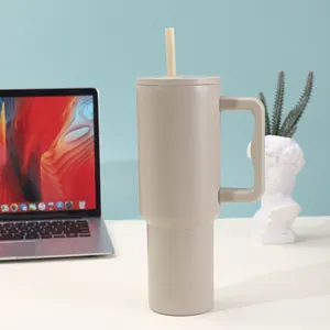 Detail of a matte beige 40oz insulated stainless steel tumbler with straw on office desk.