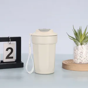Vista dettagliata di una tazza da caffè ottagonale beige in acciaio inox con cinturino di trasporto.