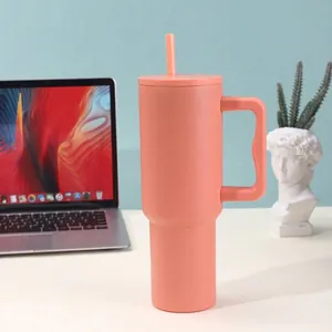 Large 40oz peach stainless steel insulated tumbler with handle and straw displayed on a desk