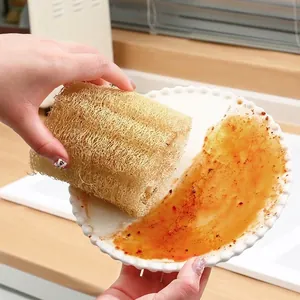 Natuurlijke loofah spons verwijert vet van een keramisch bord