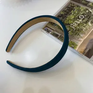 Primo piano di un cerchietto in tessuto verde petrolio con trama a spiga e fodera.