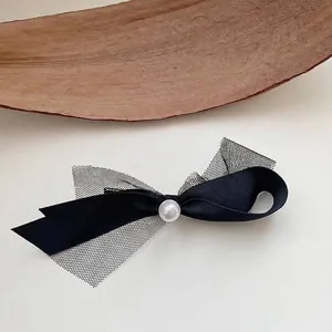Detailed view of the black ribbon bow hair clip with mesh fabric and central pearl accent