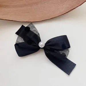 Close-up of black mesh bow hair clip featuring a delicate central pearl and tulle.
