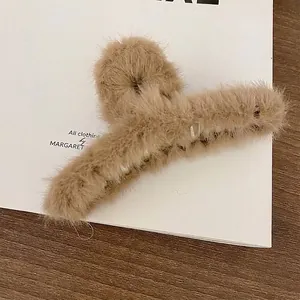 Detailed close-up of a soft milk tea brown plush hair claw clip with warm faux fur texture