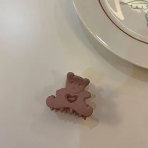 Gros plan d'une pince à cheveux mate rose poudré en forme d'ours avec un cœur évidé