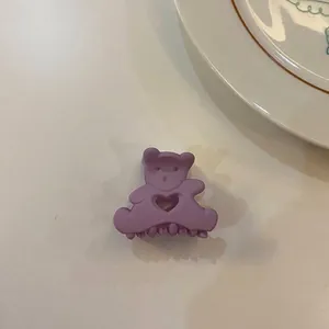 Gros plan d'une pince à cheveux violette en forme d'ours sur fond blanc.