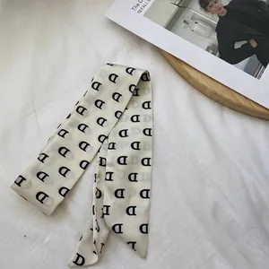 Gros plan d'une écharpe en soie avec motif de lettre D noire sur tissu crème