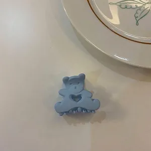 Vue détaillée d'une pince à cheveux ours bleu mat avec un motif de cœur évidé élégant