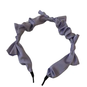 Elegant lavender satin ruffled headband with delicate bow accents on a white background