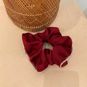 Elegant dark red satin scrunchie with sparkling rhinestone edges shown in close-up detail