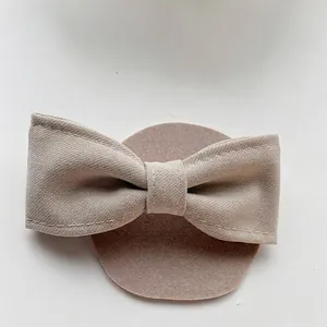 Close-up of a minimalist beige fabric bow hair clip with fine twill texture