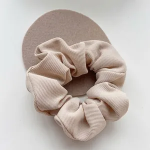 Close-up of a beige ribbed fabric French scrunchie hair tie elegant hair accessory