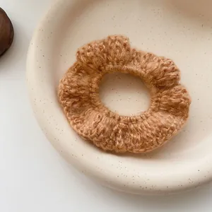 Close-up macro detail of a soft brown knitted hair scrunchie with warm crochet texture