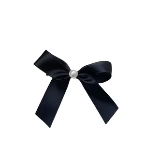 Elegant black ribbon bow hair clip featuring a delicate central pearl on white background
