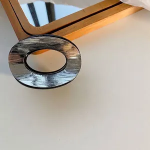 Close-up detail of a silver brushed metal oval hair claw clip for elegant hair styling
