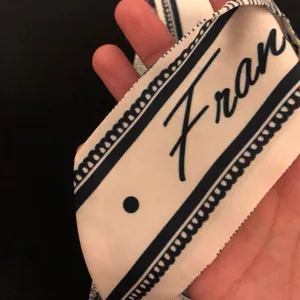 Nahaufnahme eines schmalen Seidenschals im französischen Stil mit elegantem "Fran"-Aufdruck.