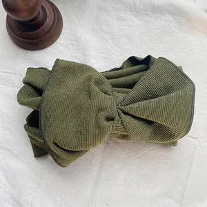 Detailed macro view of olive green ribbed fabric headband featuring a large stylish bow