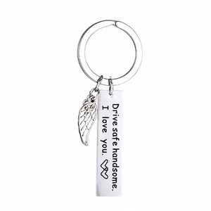 Macro detail of stainless steel keychain with 'Drive safe' engraved bar and wing charm
