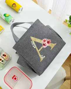 Detailed view of gray insulated lunch bag featuring a glitter gold letter A and floral print
