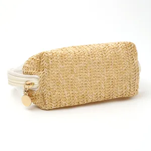Close-up detail showing the woven straw texture and gold zipper pull of a travel makeup bag