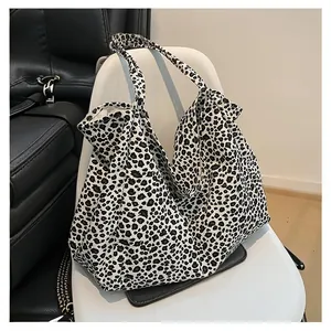 Detail view of a large leopard print canvas tote bag styled casually on a white chair.