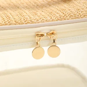 Detailed close-up of golden dual zippers on a straw-woven and PVC travel toiletry bag