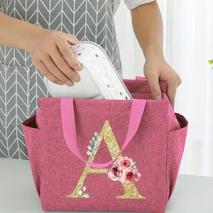 Pink insulated lunch bag with a glittery floral letter A being used with a lunch box.