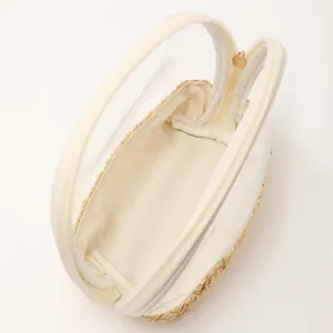 Detailed view of clear portable straw woven cosmetic bag interior and gold zipper