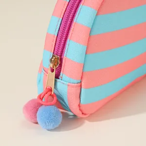 Detailopname van een gestreept make-uptasje met pompon ritssluiting